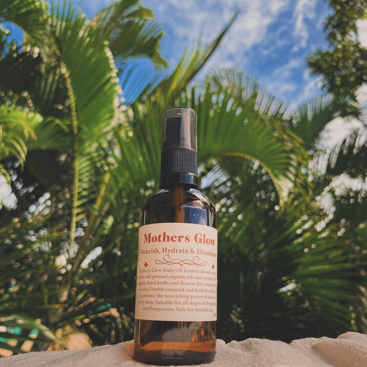 A bottle of organic body oil displayed outdoors with palm trees in the backdrop